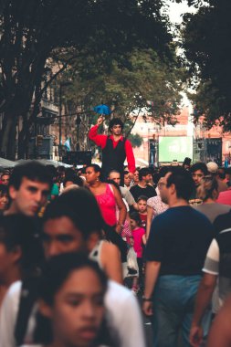 Kalabalık caddede duran küçük şemsiyeli adam.