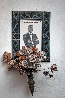 Beyaz duvarda çiçek buketi olan bir anıt.