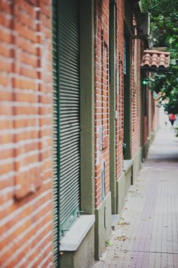 Duvarları tuğlalarla kaplı bir caddenin dikey görüntüsü.