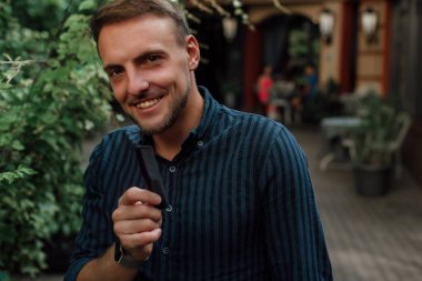 Tişörtlü bir adam gülümsüyor ve elinde tarak tutuyor.