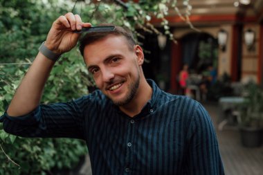 Tişörtlü bir adam gülümsüyor ve elinde tarak tutuyor.