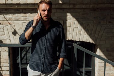 Tişörtlü bir adam telefonda konuşuyor.