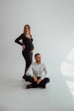 Stüdyoda beyaz bir geçmişi olan mutlu evli bir çift, hamile bir kız ve kocası.