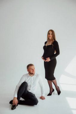 Stüdyoda beyaz bir geçmişi olan mutlu evli bir çift, hamile bir kız ve kocası.