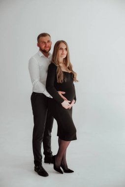 Stüdyoda beyaz bir geçmişi olan mutlu evli bir çift, hamile bir kız ve kocası.