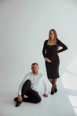 Stüdyoda beyaz bir geçmişi olan mutlu evli bir çift, hamile bir kız ve kocası.