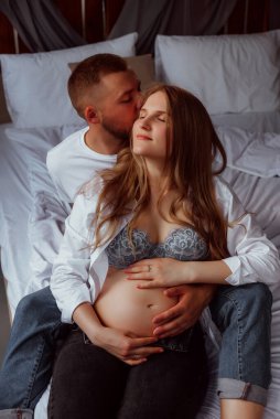 Stüdyoda beyaz bir geçmişi olan mutlu evli bir çift, hamile bir kız ve kocası.