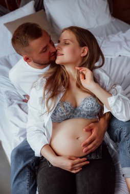 Stüdyoda beyaz bir geçmişi olan mutlu evli bir çift, hamile bir kız ve kocası.