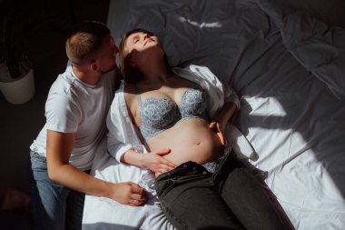 Stüdyoda beyaz bir geçmişi olan mutlu evli bir çift, hamile bir kız ve kocası.