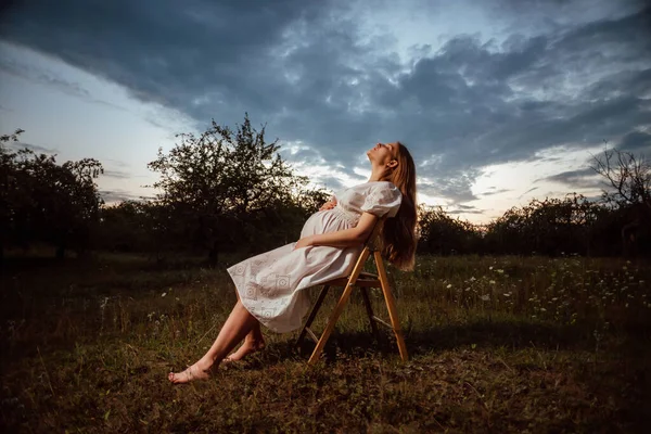 Pregnant Girl White Dress Sits Chair Garden Background Sunset — Stock Photo, Image