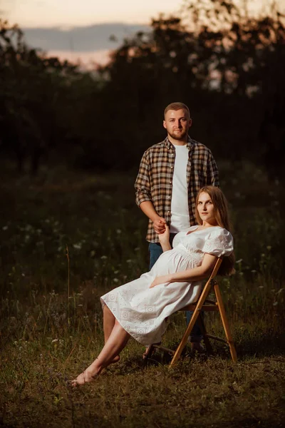 Uma Menina Grávida Vestido Branco Senta Uma Cadeira Jardim Contra — Fotografia de Stock