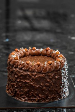 Parlak renkli bir pasta siyah bir masanın üzerinde duruyor.