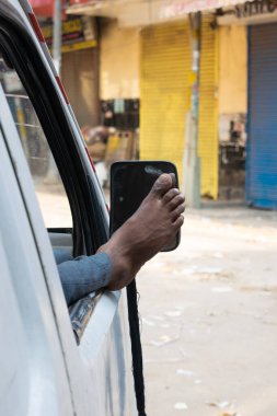 Bir sürücünün arabasının camından çıplak ayakla çıkarken rahatlatıcı bir pozisyonda