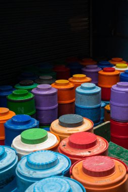 Eski çok renkli su kabı Delhi caddesinde çalışan bir işçi tarafından toplanıyor.