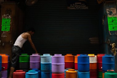 Eski çok renkli su kabı Delhi caddesinde çalışan bir işçi tarafından toplanıyor.
