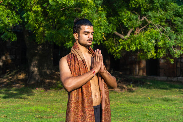 a young muscular man doing yoga and deep meditation on grass on a sunny day