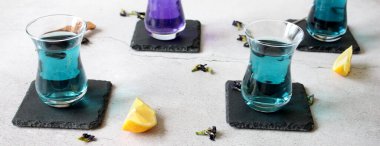 Sağlıklı içecekler, organik mavi kelebek bezelye çiçeği çayı limes ve limon, gri beton arka plan kopya alanı üstten görünüm