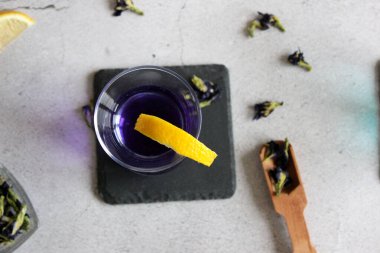 Sağlıklı içecekler, organik mavi kelebek bezelye çiçeği çayı limes ve limon, gri beton arka plan kopya alanı üstten görünüm