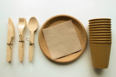 Eko kağıt sofra takımı. Kağıt bardaklar, tabaklar ve beyaz arka planda ahşap çatal bıçak takımı. Geri dönüşüm konsepti. Üst görünüm.