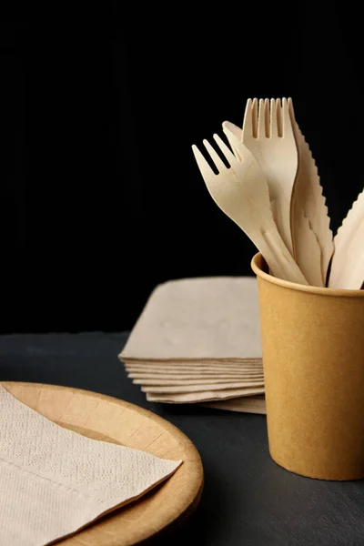 Vajilla de papel Eco artesanal. Vasos de papel, platos y cubiertos de madera sobre fondo oscuro. Concepto de reciclaje — Foto de Stock