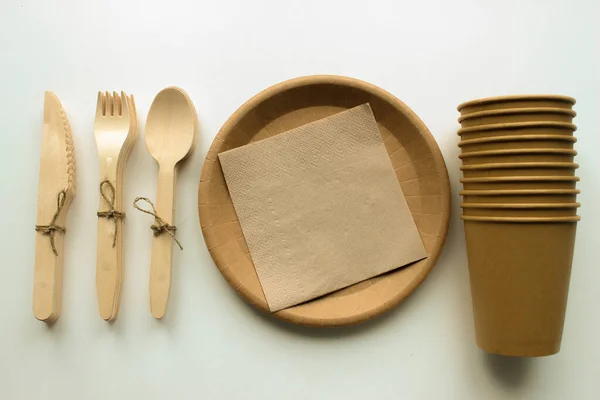 Vajilla de papel Eco artesanal. Vasos de papel, platos y cubiertos de madera sobre fondo blanco. Concepto de reciclaje. Vista superior. — Foto de Stock