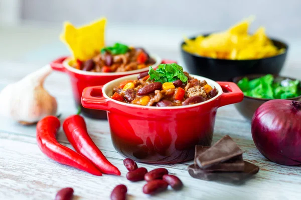 Pyszne Chili Con Carne Czerwonych Garnkach Podawane Dodatkiem Chipsów Tortilla — Zdjęcie stockowe