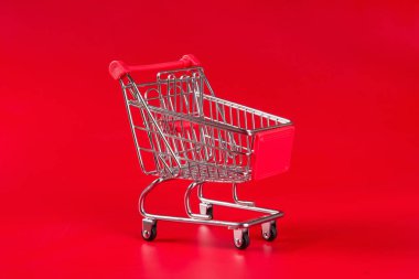 Kırmızı arkaplanda boş kırmızı alışveriş arabası.