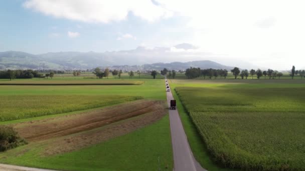 Auta a kamion jedoucí po malé postranní silnici přes krásná pole, vzdušné. — Stock video
