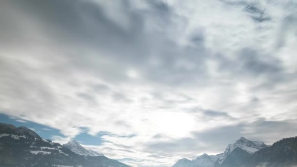 Быстро движущиеся облака над массивными снежными горными вершинами в сельской местности Швейцарии — стоковое видео
