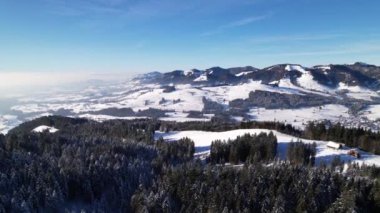 Güneşli mavi gökyüzünde, karlı orman ve tepeler üzerindeki hava manzarasını rahatlatıyor.