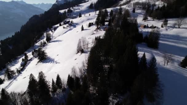 Lot dronem nad odległymi domami na śnieżnym górskim kurorcie w Szwajcarii — Wideo stockowe
