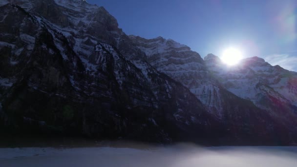 Панорамний зимовий вид на скелясту гірську стіну, вид на захід сонця, повітряна лялька ліворуч — стокове відео