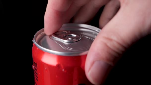 Кавказька рука відкриває червоний безалкогольний напій у повільному русі, чорний фон — стокове відео