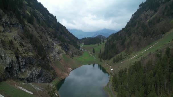 Reflective panoramic alpine lake in a Swiss mountain valley, aerial backwards Stockfilm