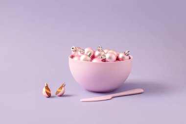 Bir kase dolusu Noel topunun yanında kesilmiş tatlı pembe Noel balosu. Noel pastası yaratıcı fikri. En az yeni yıl yemeği konsepti.