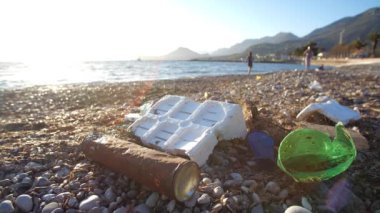 Ekolojik sorun ve çevre kirliliği kavramı. Sahile saçılmış çöpler. Kullanılmış kirli plastik şişeler. Çevre kirliliği. İnsanları arka planda bırakmak 4k