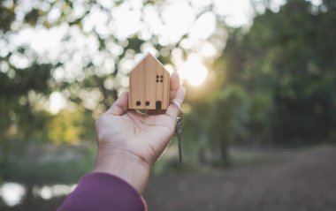 House model and key on hand for family home and real estate