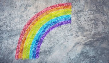 Painting rainbow colors on grunge concrete wall.