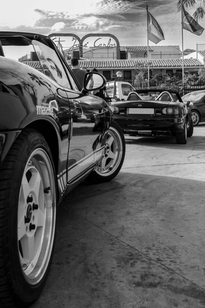 Sokakta park etmiş bir arabanın siyah beyaz fotoğrafı.