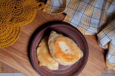Ahşap masada iki ayrı kızarmış etli kil tabak. Tatar geleneksel turtaları.