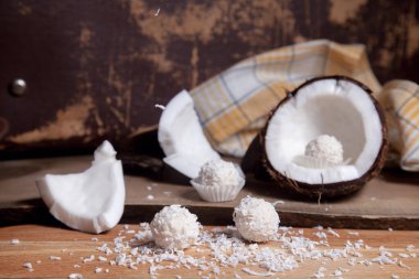 Hindistan cevizini beyaz hamurlu, hindistan cevizli ve tatlı hindistancevizli trüf mantarlı kapat. Hindistan cevizi kabuğu, hindistan cevizi taneleri, kırılmış fındık parçaları, hindistan cevizi kırıntısı ve ahşap arka planda beyaz hindistan cevizi tatlısı..