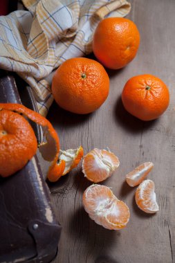 Soyulmamış taze portakal, mandalina, mandalina, mandalina, narenciye, meyvenin yarısı soyulmuş ve ahşap yaban domuzu üzerinde soyulmuş mandalina dilimleri.