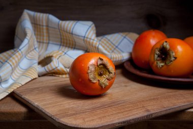 Lezzetli taze hurma meyveleri ahşap zeminde yenmeye hazır.