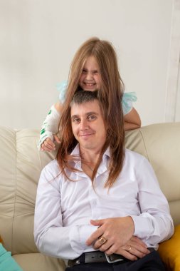 Baba ve kızı oturma odalarında eğleniyorlar. Küçük kızın eli sakat ama babasıyla olduğu için mutlu..