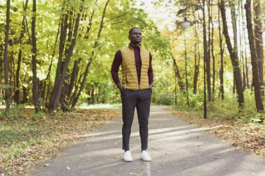 Afrikalı Amerikalı öğrenci sonbahar sezonunda parkta yürüyor.