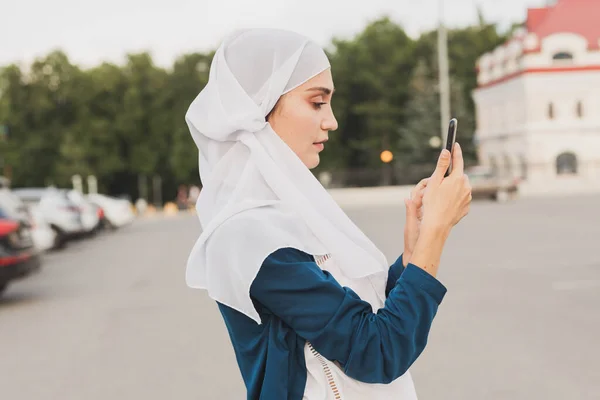 Muslimische junge Frau trägt Hijab-Kopftuch in der Stadt SMS-Handy — Stockfoto