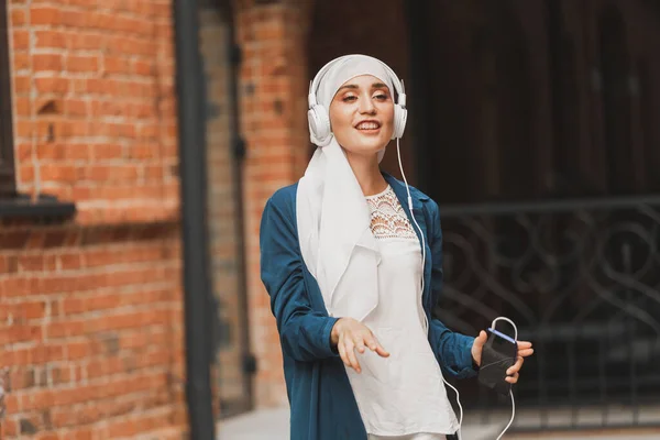 Mulher do Oriente Médio em hijab ouvir música com fones de ouvido e dançar ao ar livre. Independência da mulher e conceito de feminismo. — Fotografia de Stock