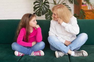 Mutlu torun ve büyükanne kanepeye oturmuş komik pozlar veriyorlar. Büyükannem evde torunuyla eğleniyor. Yaşlılar, aile ve nesil kavramı..