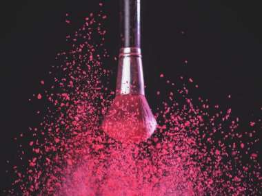 Makyaj fırça ile siyah arka plan üzerine pembe toz patlama
