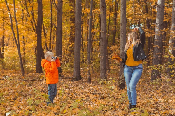 Chłopiec fotograf robi zdjęcia matce w parku jesienią. Zainteresowania, sztuka fotograficzna i koncepcja czasu wolnego. — Zdjęcie stockowe